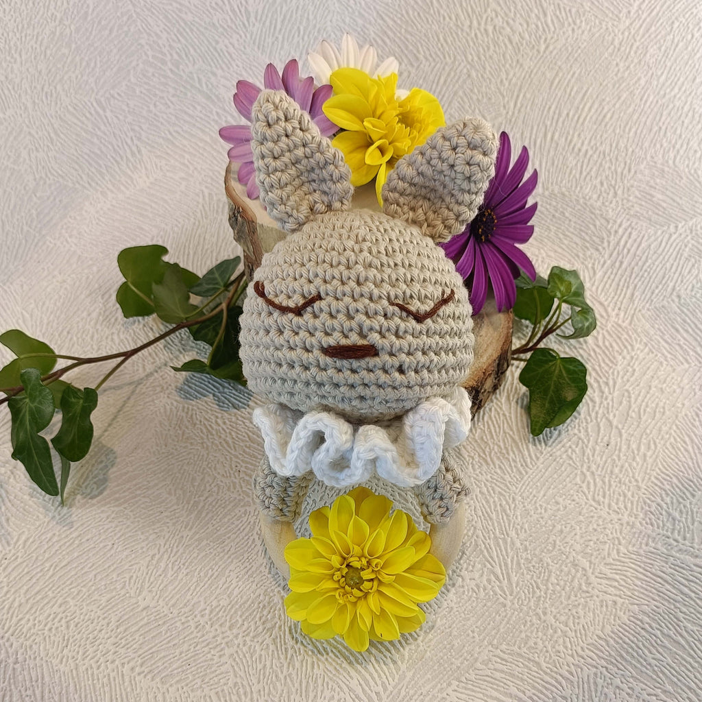Doudou lapin au crochet beige avec collerette blanche, fleurs colorées et feuilles vertes