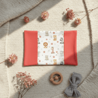 Composition à plat sur couverture en maille : protège carnet de santé safari ouvert, accompagné d'un hochet en bois et de fleurs séchées.