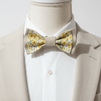 Gros plan d'un nœud papillon artisanal à motifs fleurs jaunes sur un buste de couture avec veste de costume beige.
