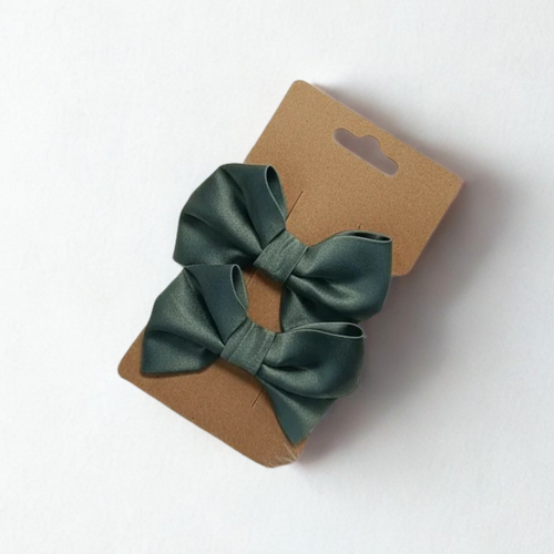 Duo de barrettes nœud en satin vert sauge sur carte kraft, accessoire coiffure cérémonie enfant.