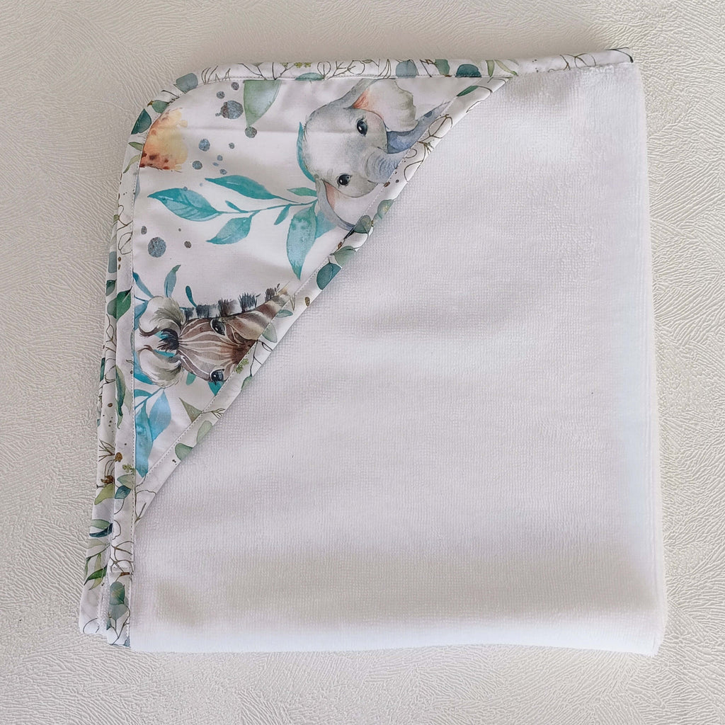 Cape de bain bébé personnalisable pliée vue de dessus, bordure motif éléphant et animaux safari aquarelle tons bleus et verts, éponge blanche, faite main L'Atelier de Megh