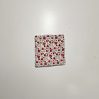 Gros plan sur une lingette lavable carrée en coton à motif petites fleurs rouges.