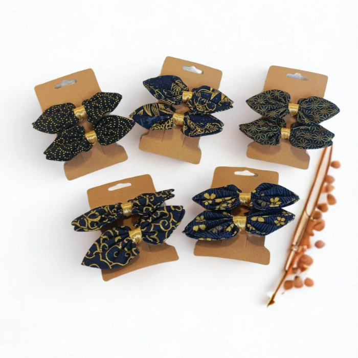 Vue d'ensemble de la collection de barrettes à nœud en tissu japonais bleu marine et doré. 5 motifs traditionnels différents (fleurs, géométrique) présentés sur cartes kraft.