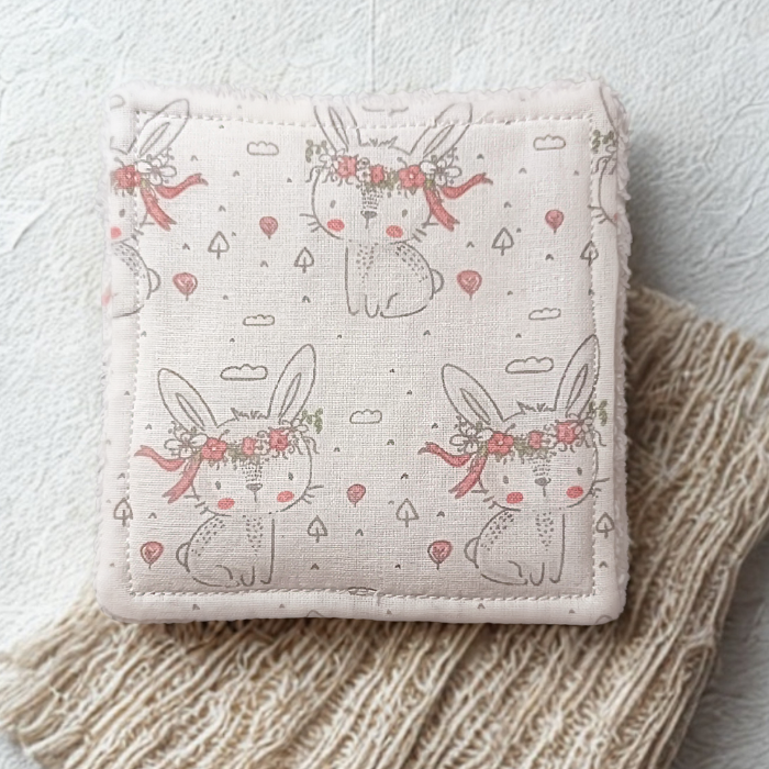 Gros plan sur le tissu coton certifié Oeko-Tex : motif lapin gris et feuillage vert tendre.