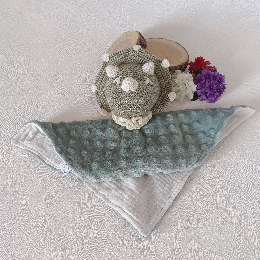 Doudou dinosaure au crochet vert sauge posé à plat, recto minky vert sauge à bulles et verso mousseline blanche