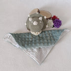 Doudou dinosaure au crochet vert sauge posé à plat, recto minky vert sauge à bulles et verso mousseline blanche