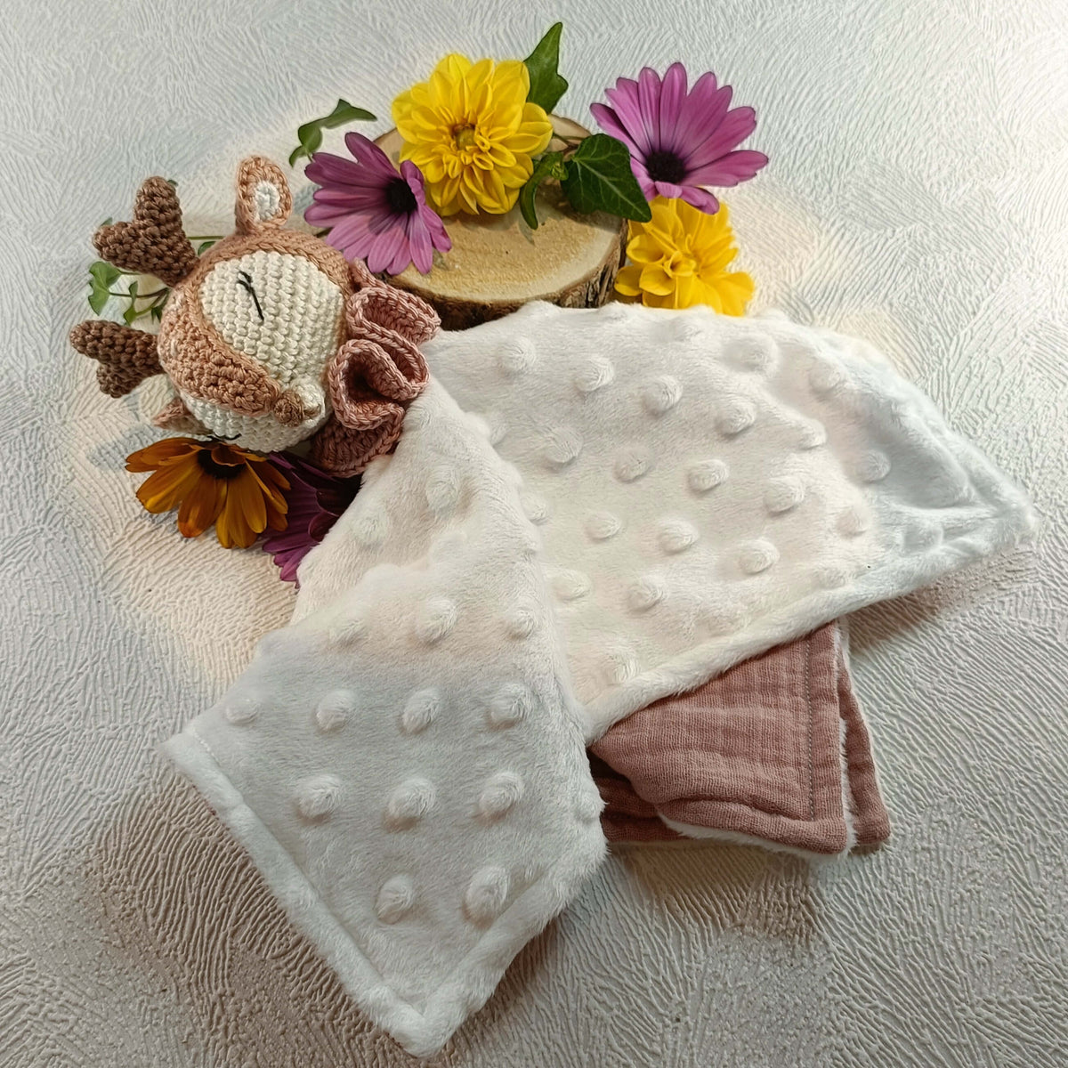 Doudou bébé tête de faon en crochet, tissu blanc à pois, fleurs décoratives colorées.