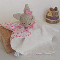 Doudou lapin au crochet avec petit nœud rose, corps en gaze de coton blanche et revers à motifs petites fleurs roses.