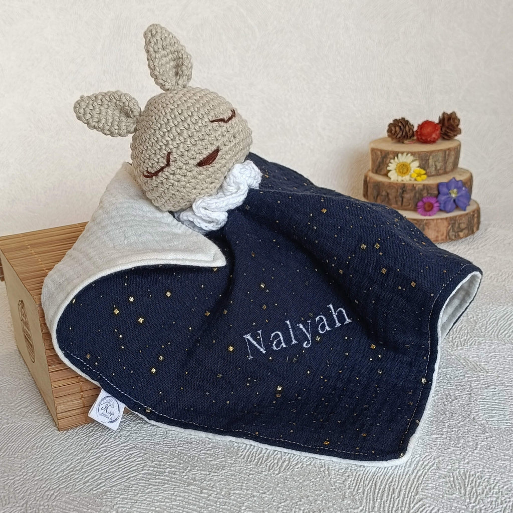 Doudou lapin au crochet bleu marine avec broderie personnalisée du prénom Nalyah en fil blanc.