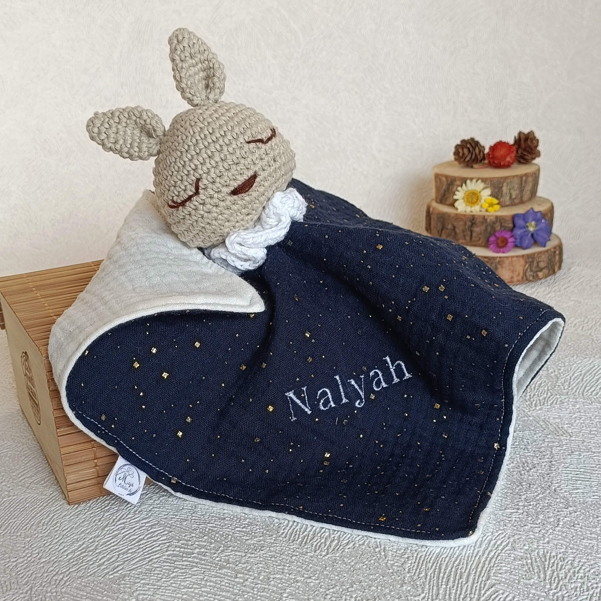 Doudou lapin au crochet bleu marine avec broderie personnalisée du prénom Nalyah en fil blanc.