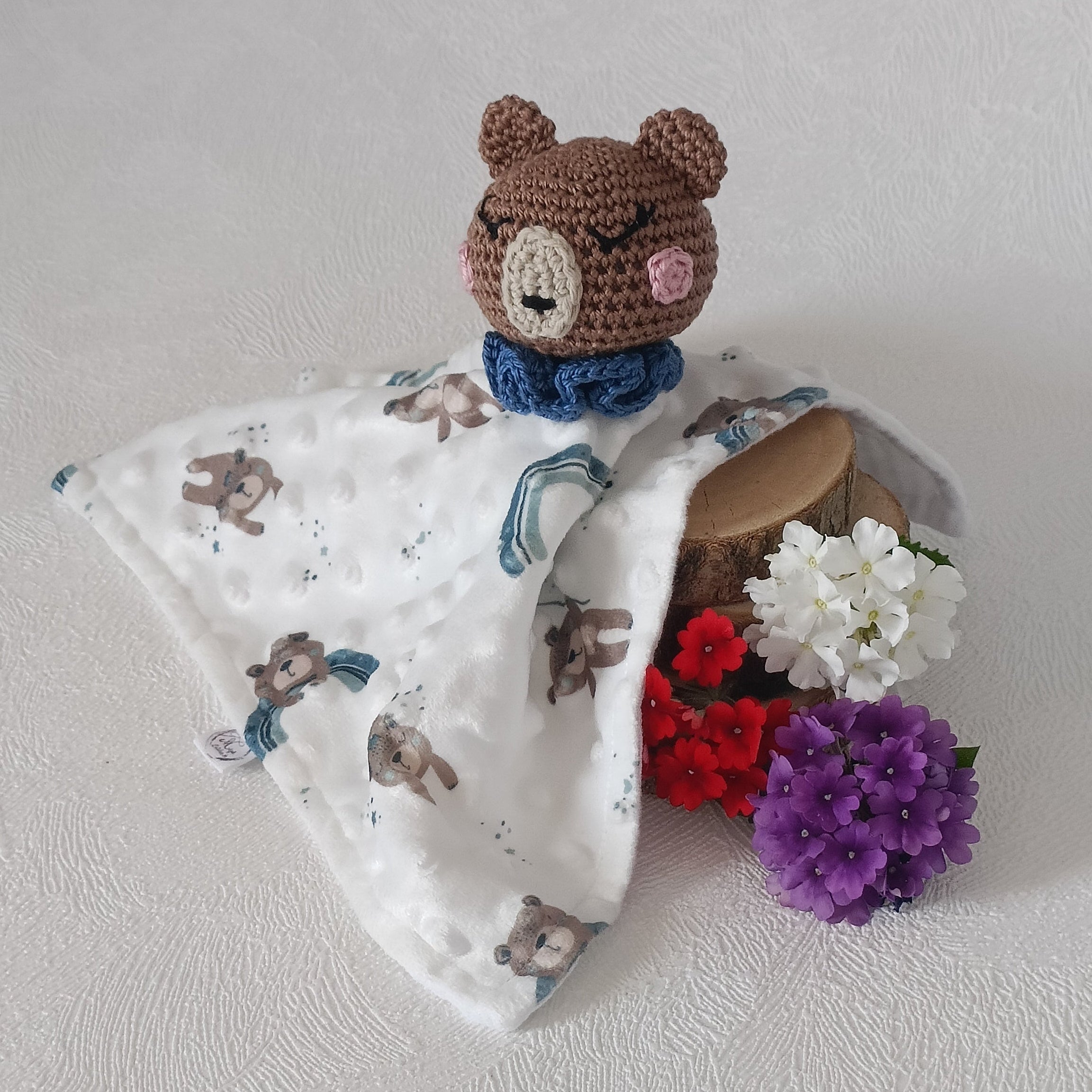 Doudou ours au crochet marron col bleu sur lange imprimé oursons arc-en-ciel, doublure minky blanc, vue trois quarts