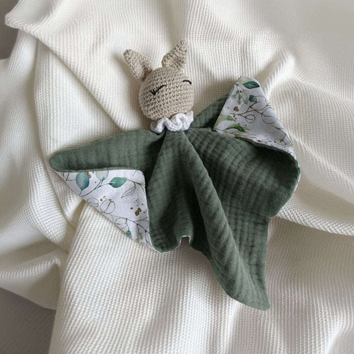 Doudou plat avec tête de lapin beige au crochet, corps en double gaze de coton vert eucalyptus et revers motif feuillage.
