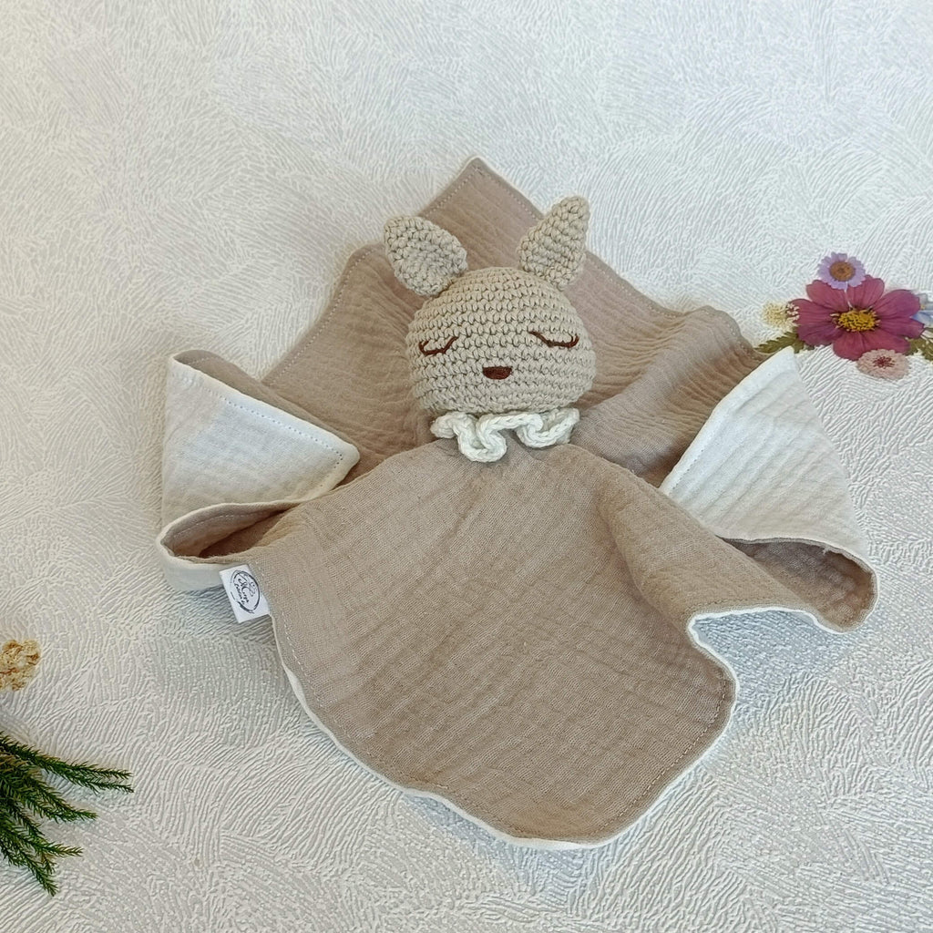 Vue à plat d'un doudou lapin artisanal beige en coton, idéal comme cadeau de naissance mixte.