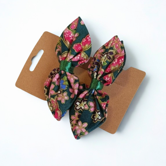 Duo de barrettes à cheveux forme nœud en tissu japonais vert sapin orné de fleurs roses et touches dorées. Centre du nœud en ruban vert satiné.