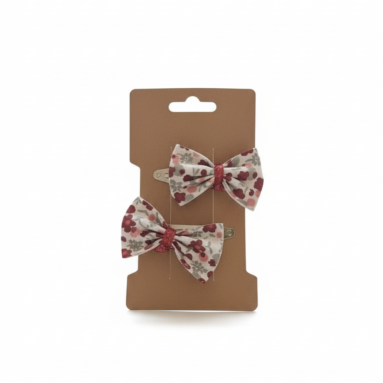 Duo de barrettes clic-clac pour cheveux avec nœud en tissu floral style Liberty rouge et bordeaux, présentées sur une carte kraft. Accessoire coiffure fille fait main.