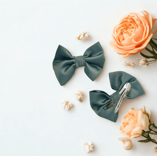 Duo de barrettes à cheveux forme nœud en satin vert sauge. Vue recto et verso montrant l'attache clic-clac métallique adaptée aux enfants. Décoration florale mariage.