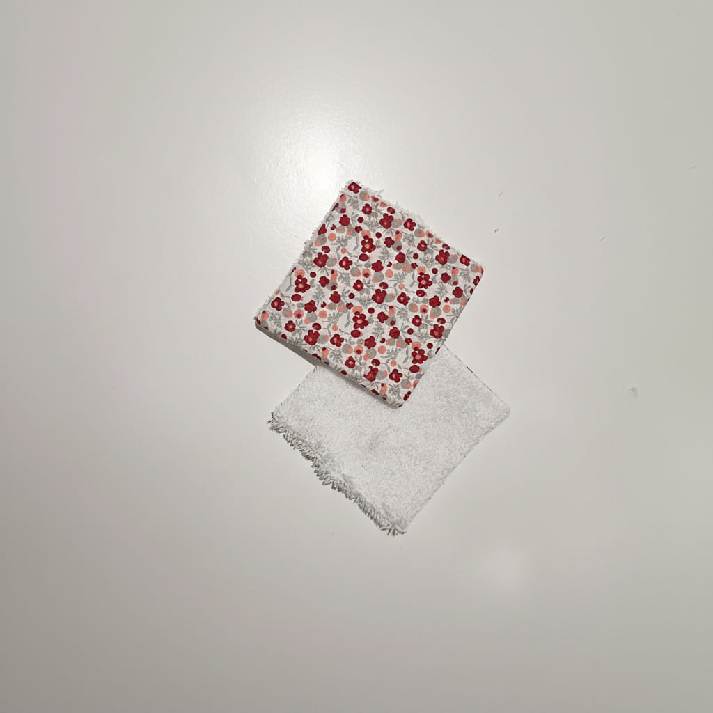 Lingettes lavables vues recto verso : motif fleurs rouges et face éponge bambou blanche.