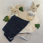 Doudou lapin crocheté avec anneau de dentition en bois et lapin crocheté sur fond clair décoré de feuilles.