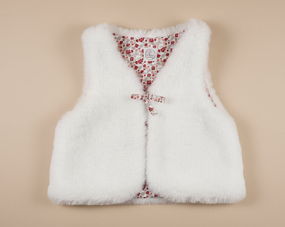 Gilet de berger pour bébé en fausse fourrure blanche et doublure fleurie. Vêtement chaud et chic fait main.