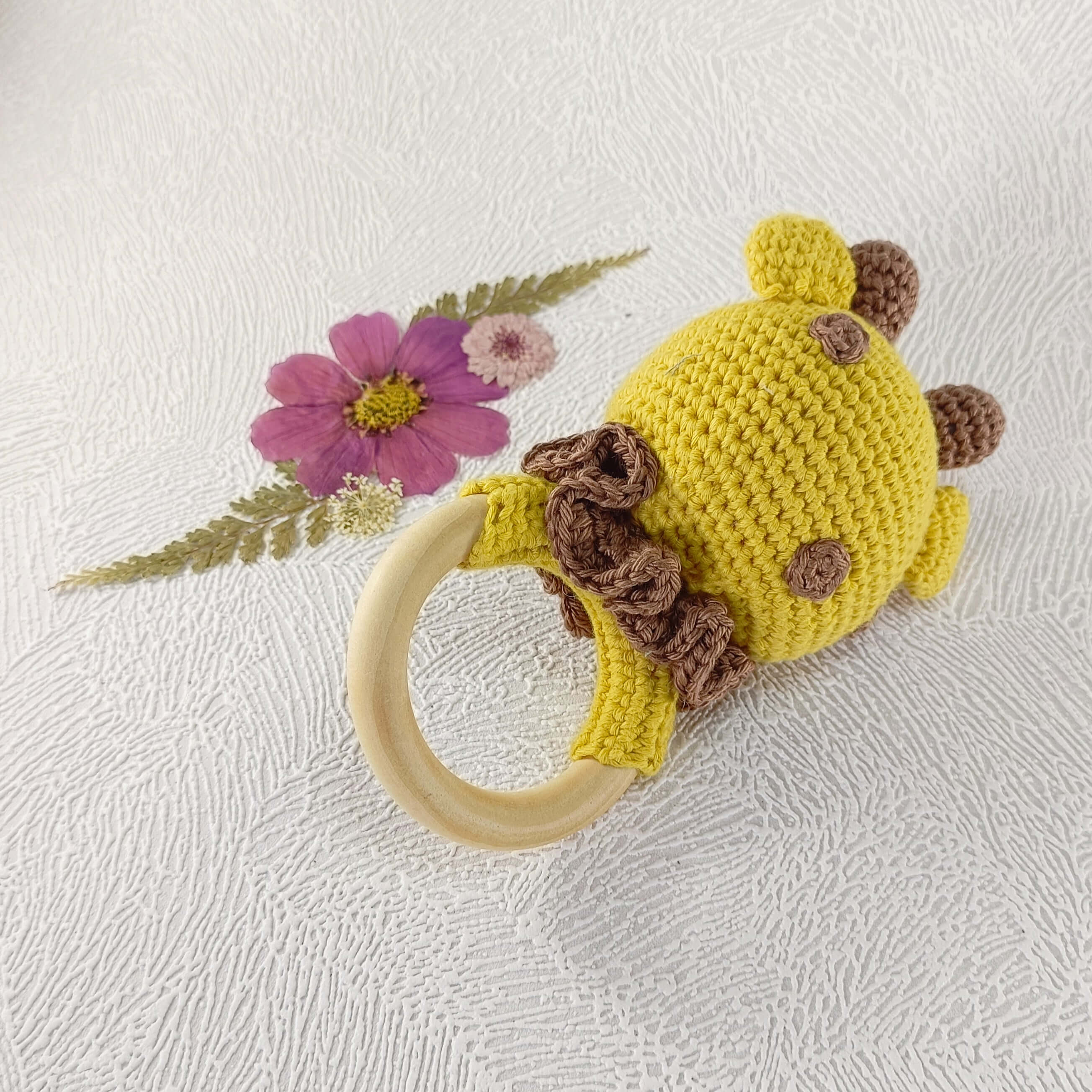 Vue arrière d'un hochet girafe artisanal en crochet montrant les détails des taches marron.