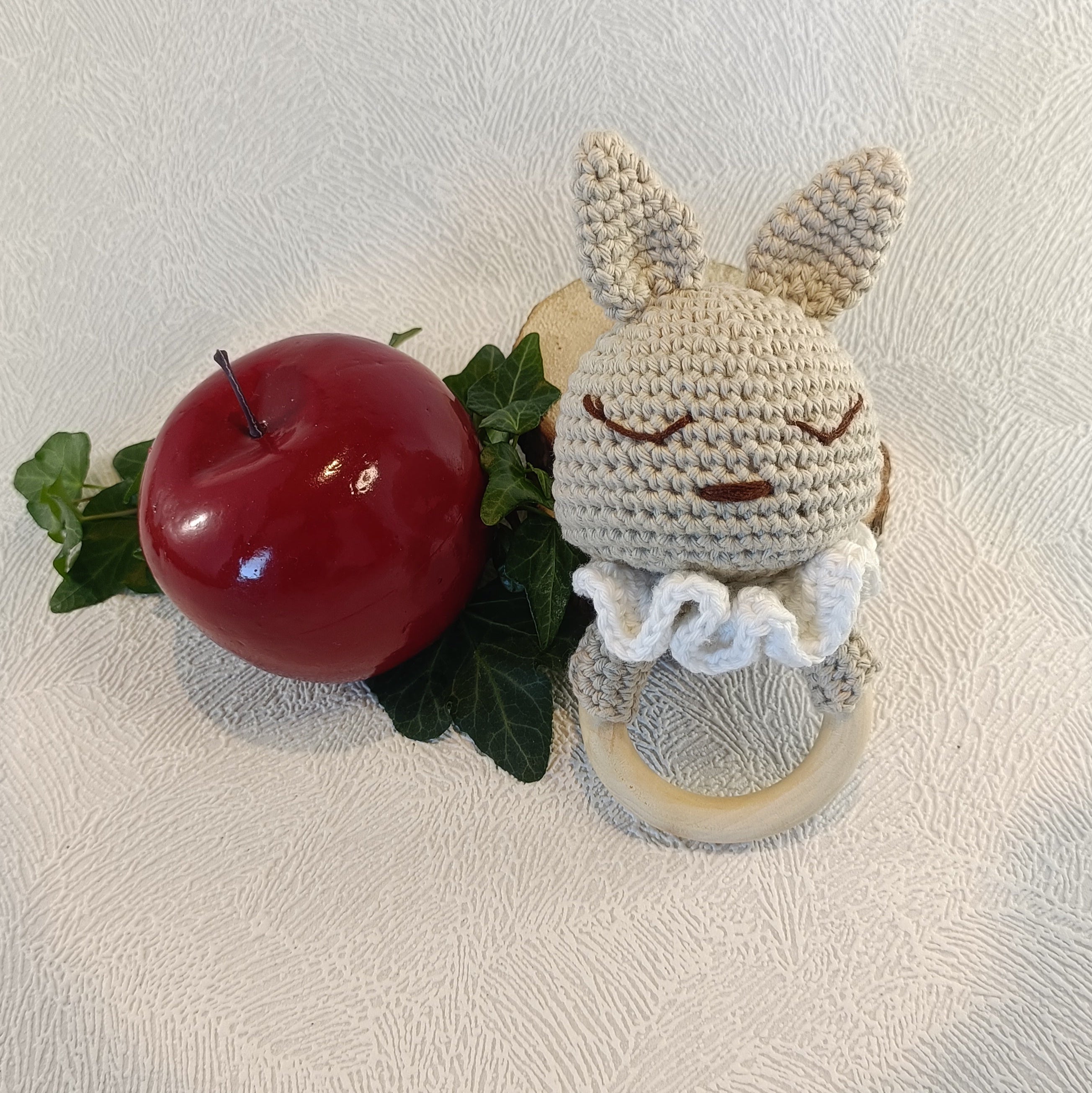 Hochet lapin beige au crochet posé près d’une pomme rouge
