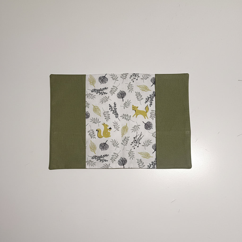 Vue dépliée de la couverture de carnet de santé montrant l'imprimé animaux de la forêt (renard, écureuil) et feuilles sur fond blanc.