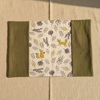 Vue dépliée de la couverture de carnet de santé montrant l'imprimé animaux de la forêt (renard, écureuil) et feuilles sur fond blanc.