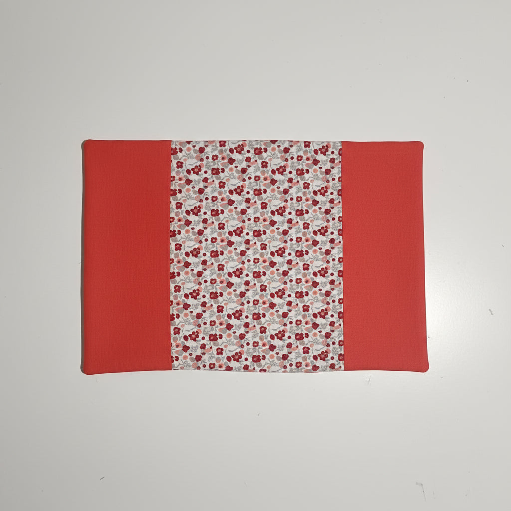 Vue intérieure dépliée d'un protège carnet de santé : tissu central à motif liberty (petites fleurs rouges et grises) et rabats latéraux unis couleur rouge brique.