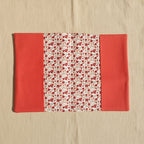 Vue intérieure dépliée d'un protège carnet de santé : tissu central à motif liberty (petites fleurs rouges et grises) et rabats latéraux unis couleur rouge brique.