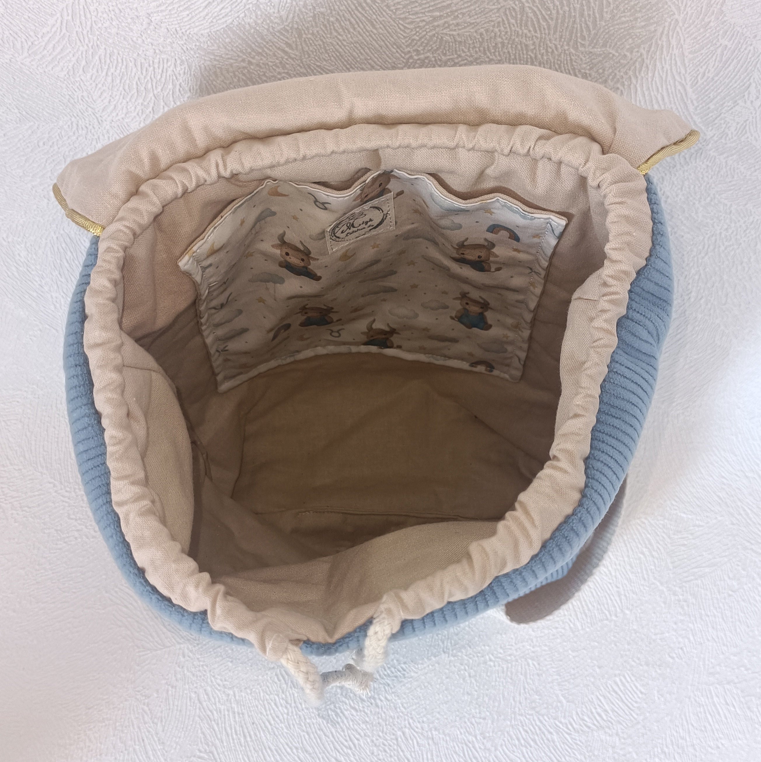 Intérieur du sac à dos enfant montrant la poche intérieure et l'étiquette L'Atelier de Megh