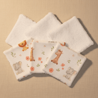Lot de lingettes lavables bébé étalées, motif animaux de la savane (lion, girafe, éléphant) et éponge bambou blanche.