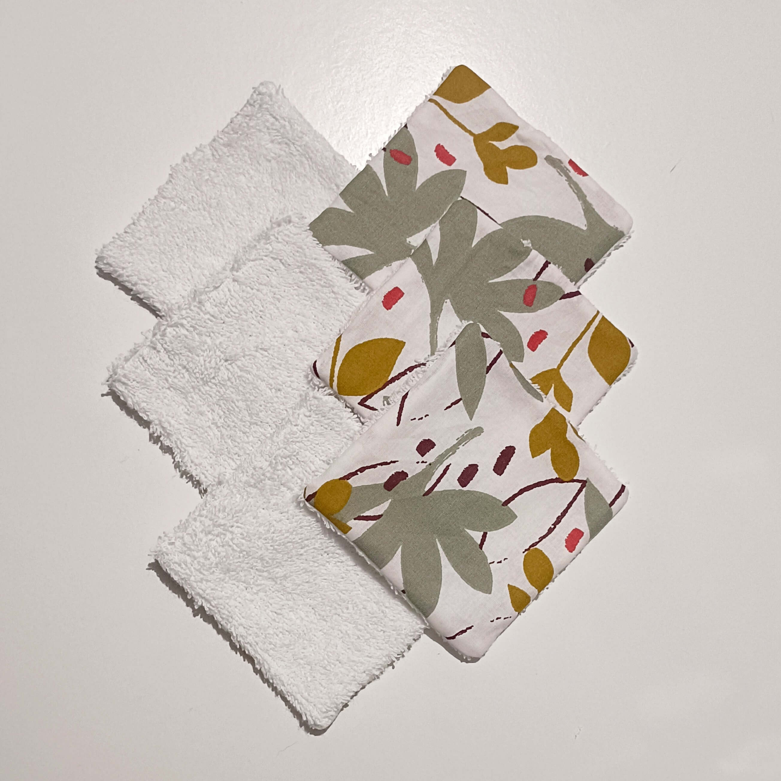 Lot de lingettes lavables bébé faites main, recto éponge blanche et verso motif floral sauge et ocre, disposées en éventail