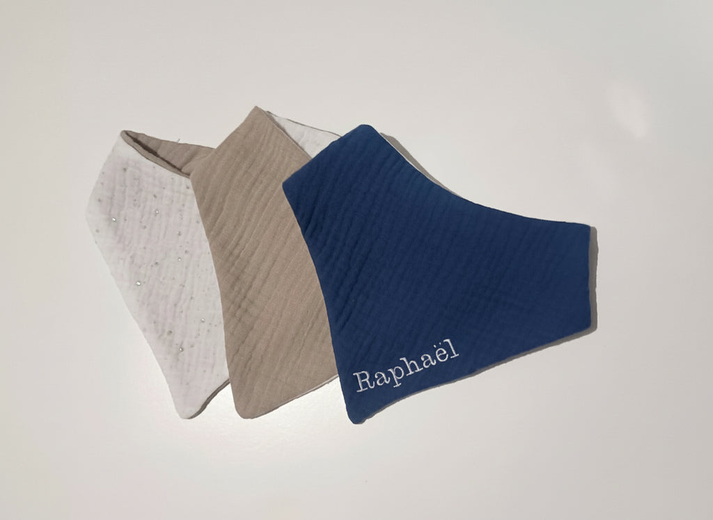 Trio de bavoirs bandana pour garçon en double gaze : bleu marine personnalisé Raphaël, beige sable et blanc à pois argentés.