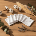 Mise en scène douce d'un lot de lingettes lavables bébé motif coeur. Décoration nature avec feuilles et fleurs de coton sur fond bois.