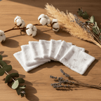 Mise en scène douce d'un lot de lingettes lavables bébé motif coeur. Décoration nature avec feuilles et fleurs de coton sur fond bois.