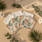 Mise en scène douce d'un lot de lingettes lavables bébé motif tigre et jungle. Décoration nature avec feuilles de palmier et fleurs de coton sur fond beige.