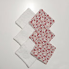 Disposition de 6 lingettes lavables alternant le côté tissu à fleurs rouges et le côté éponge blanche.