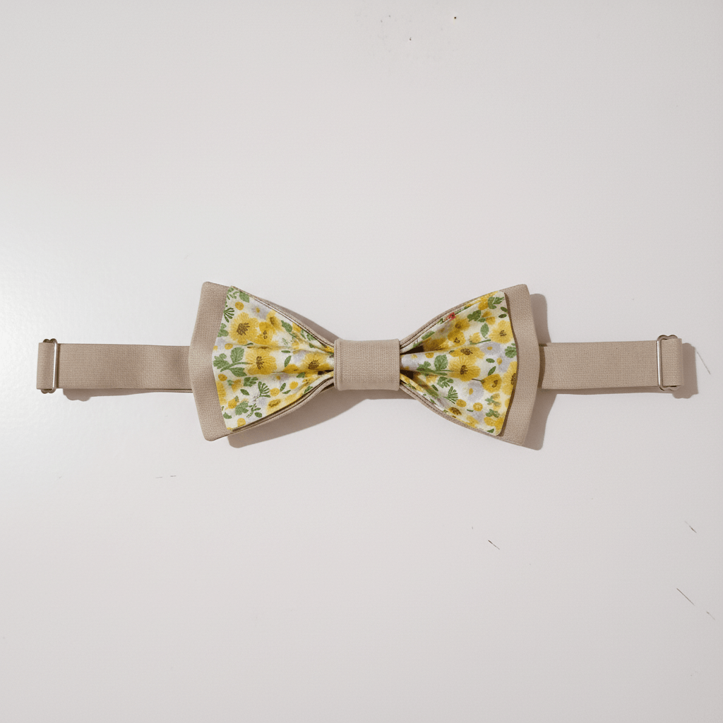 Nœud papillon double épaisseur beige et fleuri jaune présenté à plat montrant sa forme symétrique et son attache.