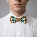 Gros plan sur le cou d'un homme portant un nœud papillon double couleur caramel et tissu floral vert et blanc.