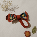 Nœud papillon artisanal réversible terracotta et motif floral coloré, mis en scène avec gypsophile et rose séchée, fait main L'Atelier de Megh