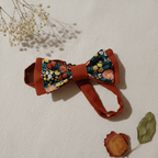 Nœud papillon artisanal réversible terracotta et motif floral coloré, mis en scène avec gypsophile et rose séchée, fait main L'Atelier de Megh
