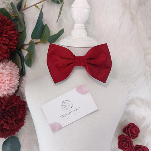Nœud papillon enfant en satin rouge bordeaux présenté sur un mannequin. Vue portée au cou pour un look de fête élégant ou une tenue de Noël.