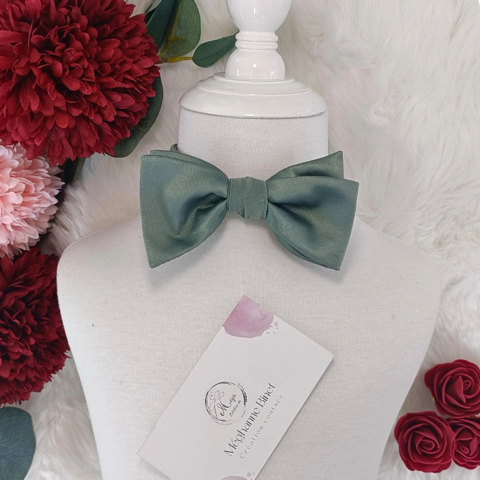 Nœud papillon enfant en satin vert sauge présenté sur un mannequin. Vue portée au cou pour un look de cérémonie élégant.