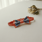 Nœud papillon enfant réglable en terracotta et tissu bleu à fleurs délicates, posé sur table blanche avec bouquet de fleurs séchées, fait main L'Atelier de Megh