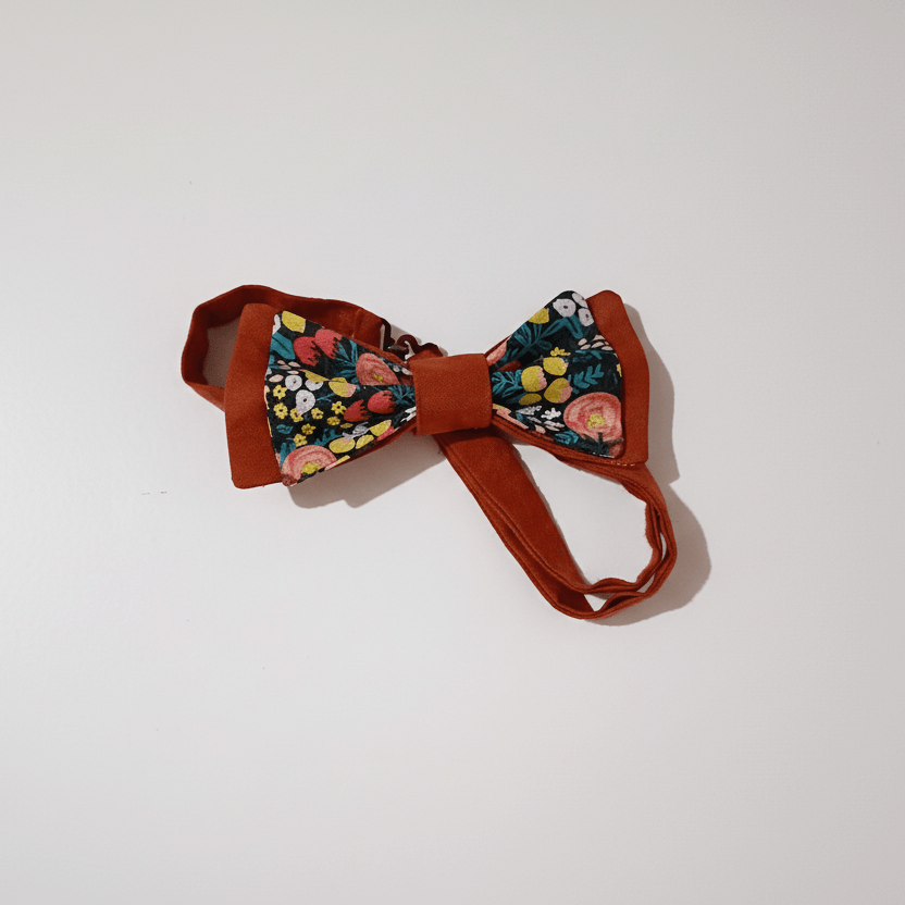 Nœud papillon artisanal réglable terracotta et motif floral coloré foncé posé à plat sur fond blanc, fait main L'Atelier de Megh