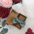 Nœud papillon enfant vert sauge présenté dans sa boîte cadeau en kraft. Emballage soigné et artisanal, idéal pour offrir.