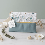 Petite pochette plate bi-matière associant un velours côtelé vert sauge et un imprimé aux délicates feuilles d'eucalyptus, souligné par un passepoil doré.