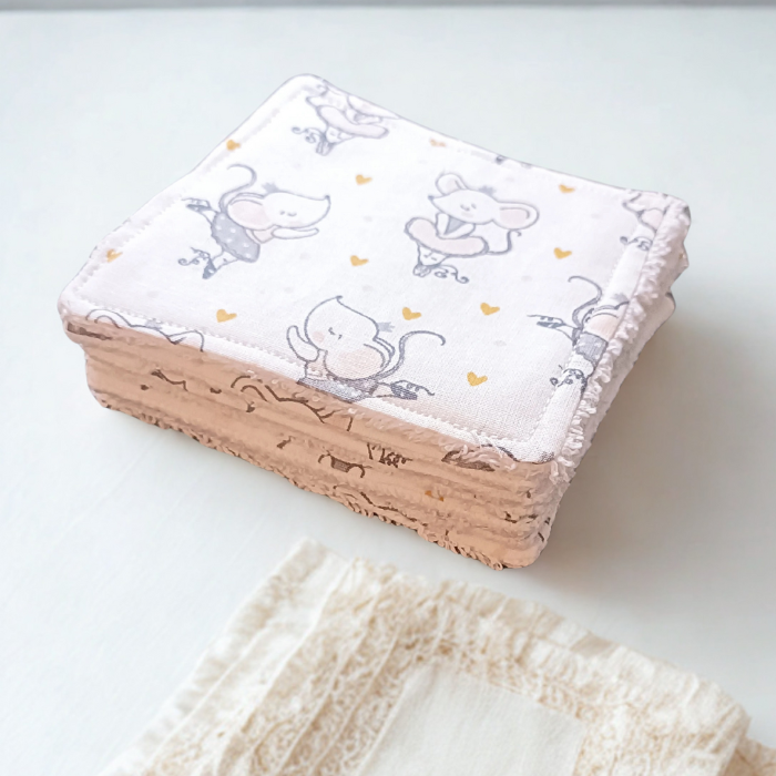 Pile de lingettes bébé pliées montrant l'épaisseur moelleuse de l'éponge de bambou. Motif souris ballerine rose et gris.