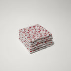 Pile soignée de lingettes réutilisables au motif fleurs champêtres rouges et roses.