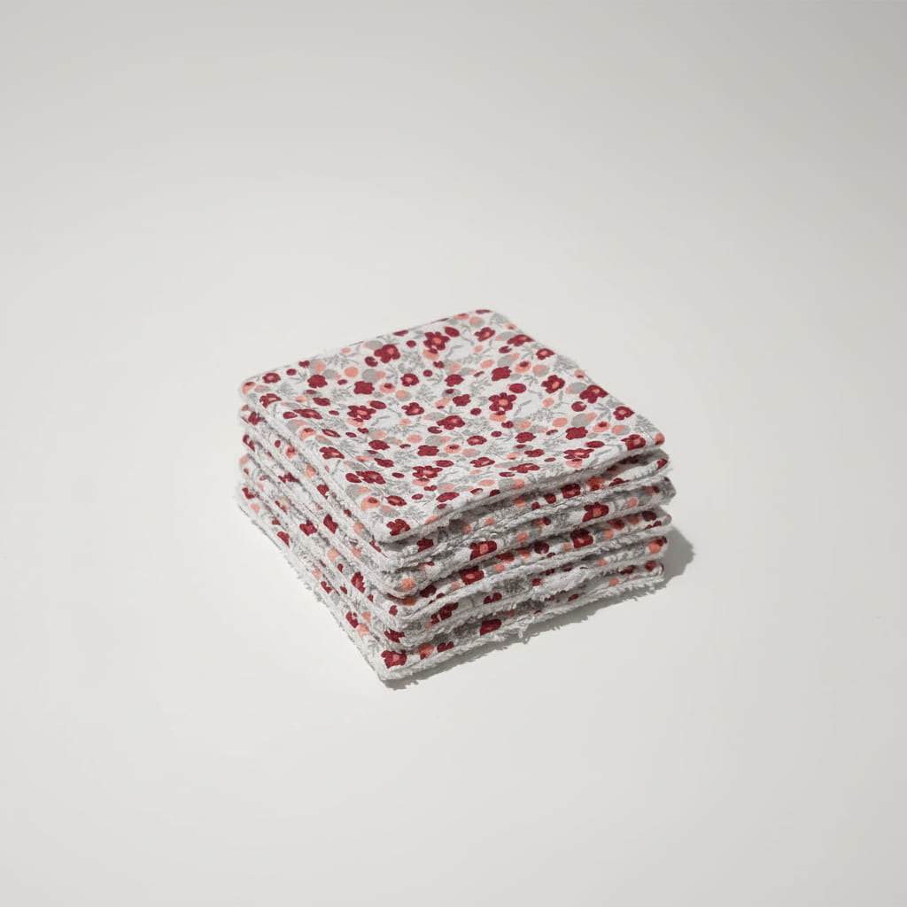 Pile soignée de lingettes réutilisables au motif fleurs champêtres rouges et roses.